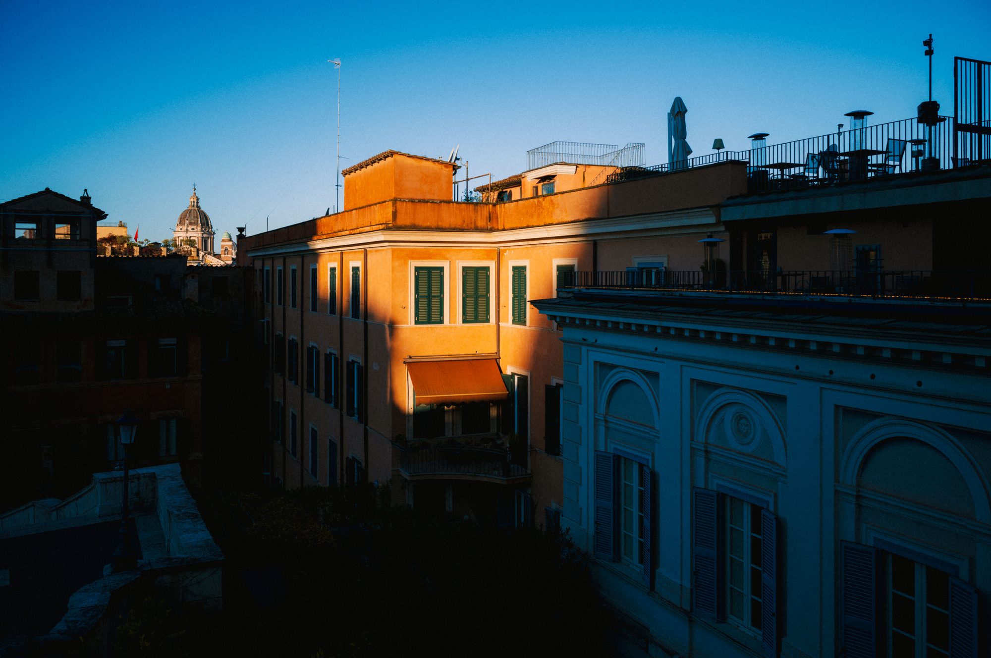Last sunlight sets one orange house aglow between rooftops already in blue shadow.