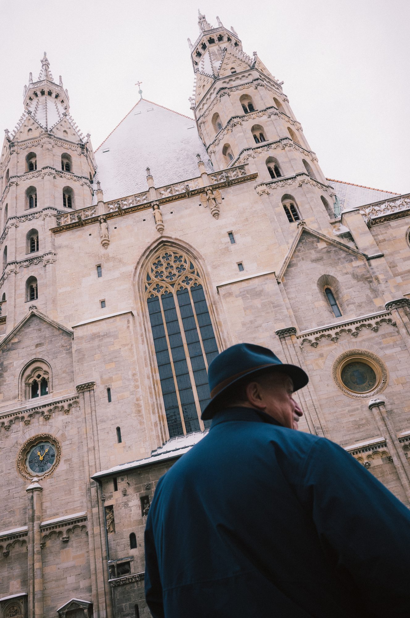 A man in a hat, seen from behind, before the west front of St. Stephen’s Cathedral.