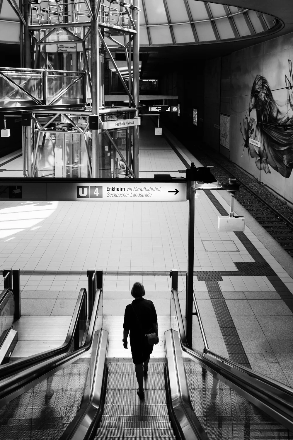 A lone silhouette rides an escalator down into a station.