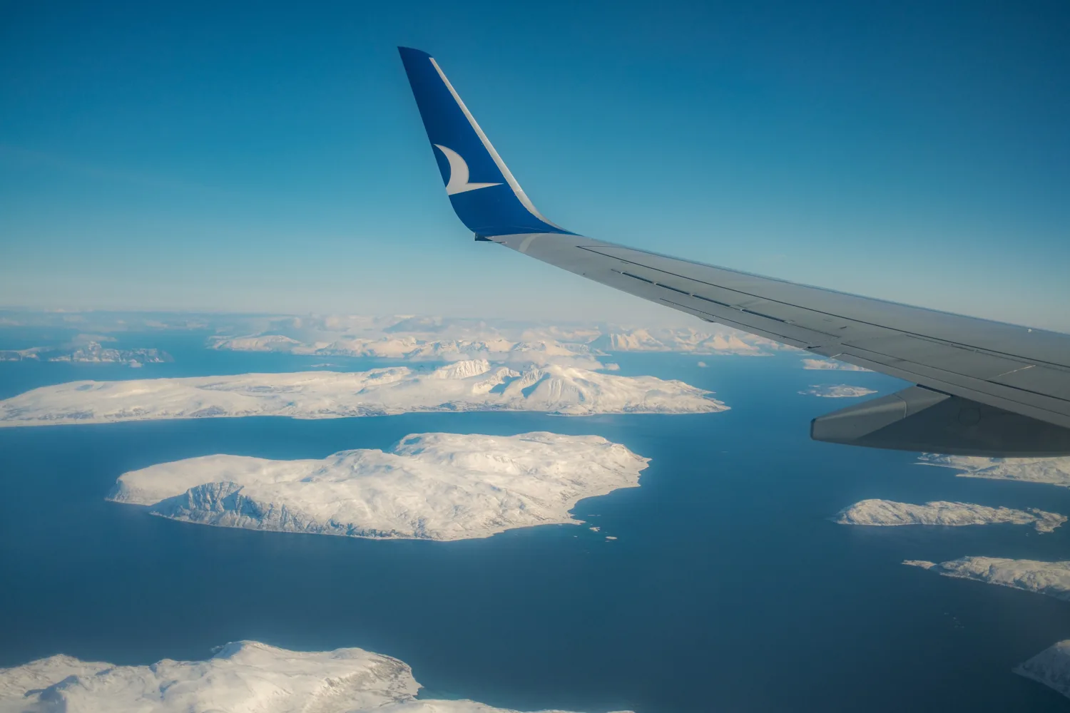An aircraft wing above the snow-covered Arctic on the way out.