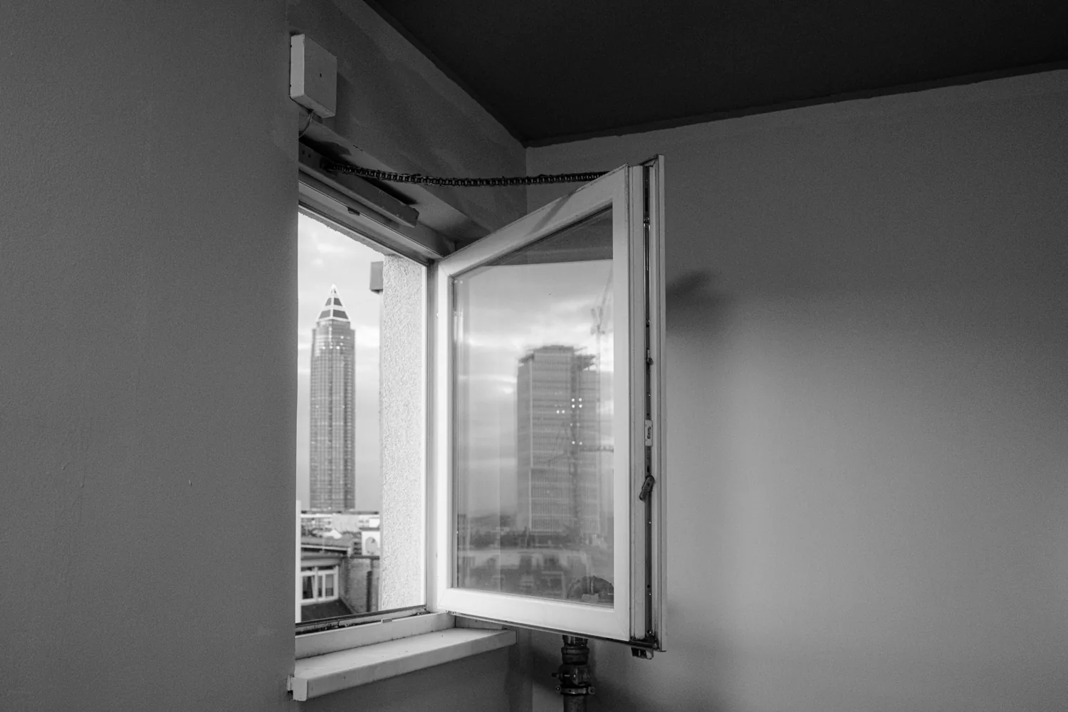 An empty room with an open window looking out to the distant skyline.